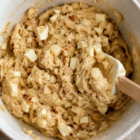 Macadamias tostadas picadas y trozos de chocolate blanco doblados en masa para galletas, fotografía editorial de libros