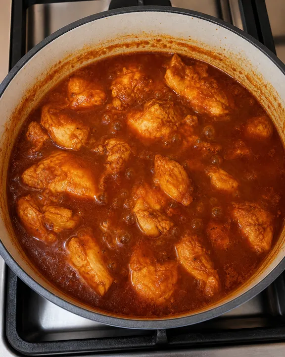 Pollo cocinándose en salsa de enchilada burbujeante