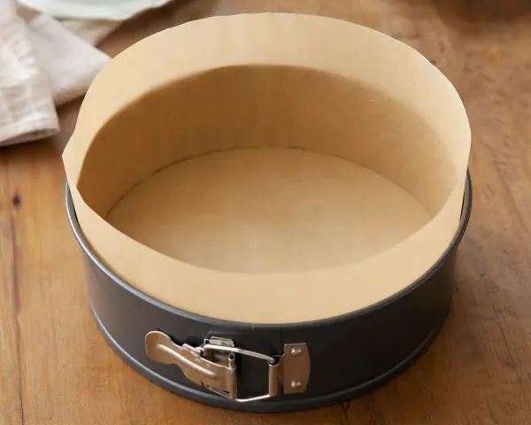 Round springform pan lined with tall baking paper