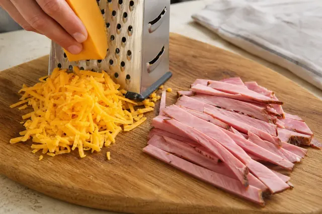 Grated cheddar beside sliced strips of ham