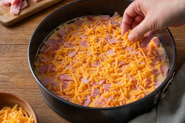 Ham and grated cheddar spread over the first batter layer