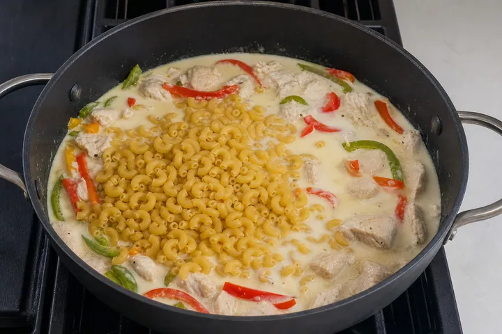 Macaroni, cream, and stock added to the frying pan