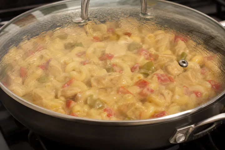 Creamy macaroni simmering in a deep frying pan