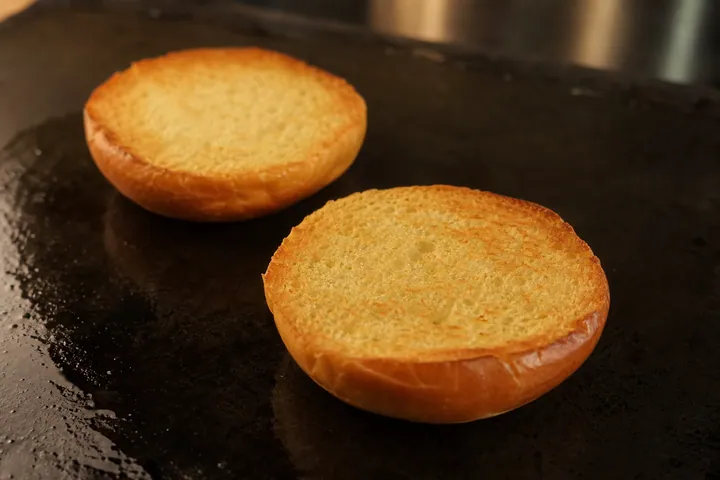 Brioche bun halves lightly toasted cut-side down on a griddle