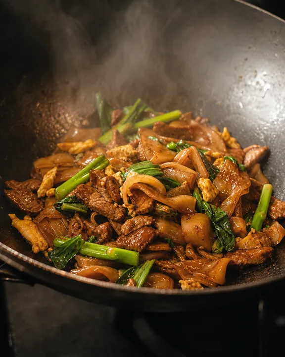 Fideos oscuros salteados con hojas marchitas
