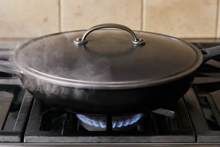 Una sartén honda tapada mientras se cocina el arroz
