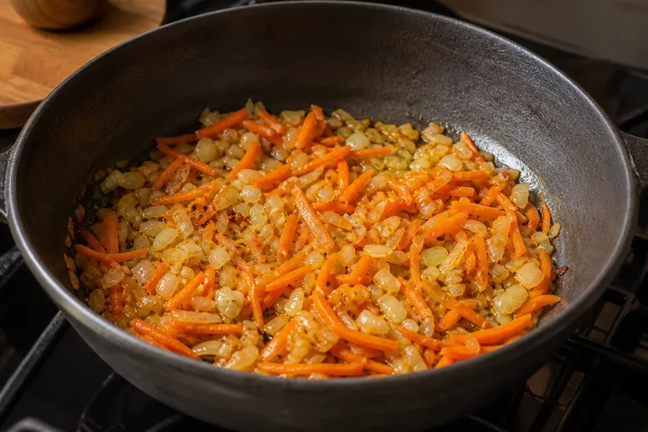 Onion and carrot strips sautéing until soft and caramelized