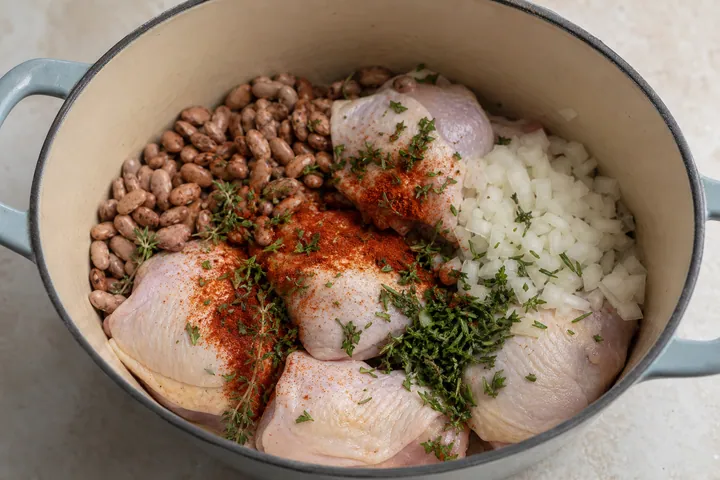 Alubias, pollo, cebolla y condimentos en una olla