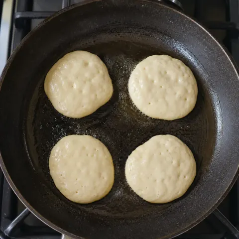 ארבעה פנקייקים קטנים מתבשלים במחבת משומנת