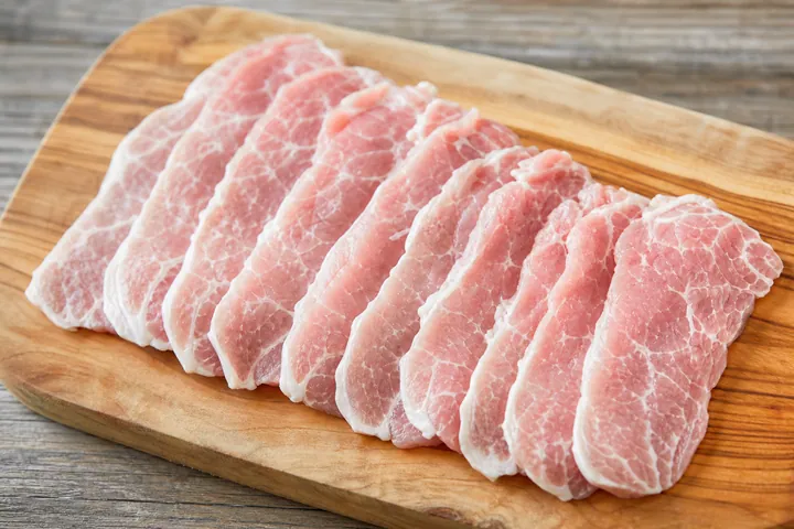 Thin raw pork slices on a cutting board