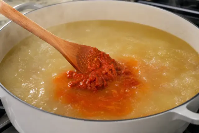 Pasta de curry rojo removida en caldo de pollo