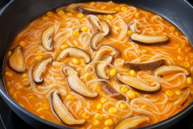 Setas shiitake y maíz dulce cocinándose con fideos de arroz