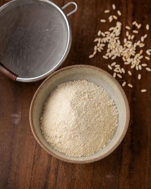 Ground roasted rice powder in a bowl beside a sieve