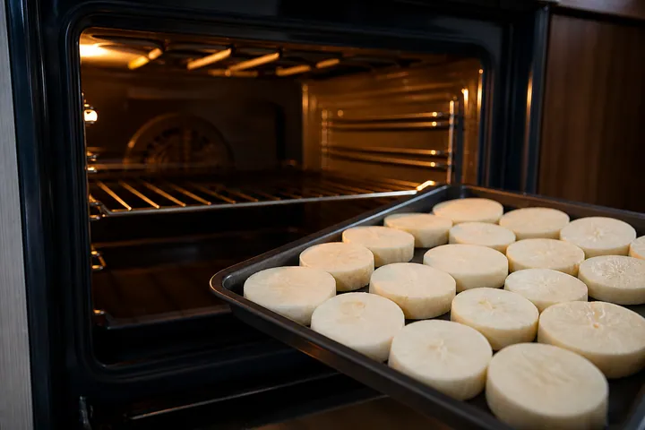 Preheated oven beside a tray of cassava slices