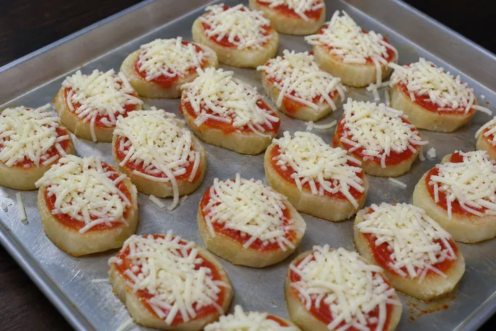 Cassava slices with tomato sauce and shredded mozzarella on a tray