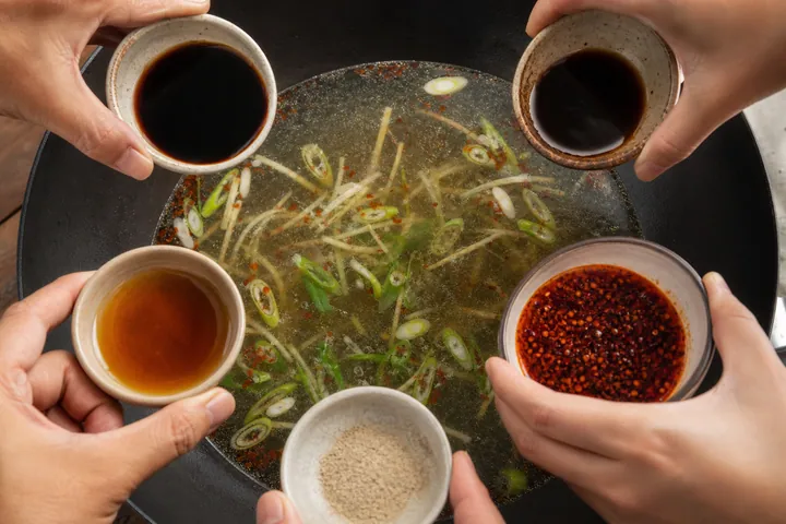 Al caldo del wok se le añade salsa de soja, vinagre oscuro, aceite de sésamo, pimienta blanca y aceite de chile.