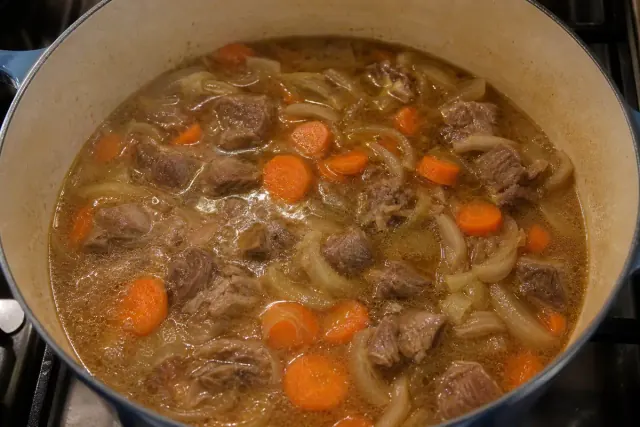Guiso de cordero con zanahorias, cebolla y caldo de verduras en una olla