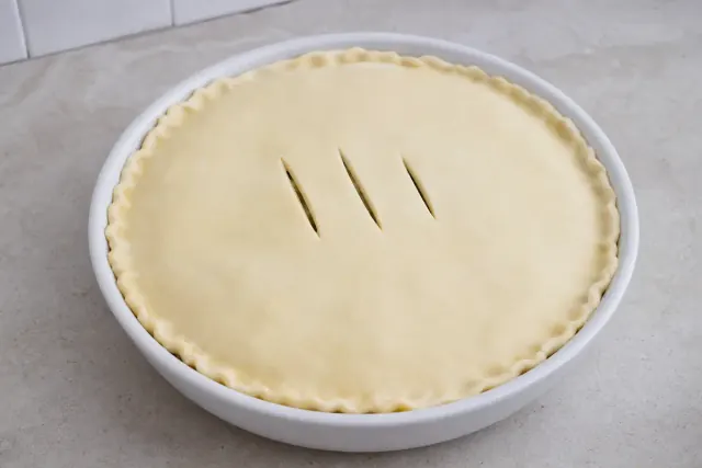 Pastel de cordero sin hornear cubierto con masa quebrada y tres ranuras de vapor
