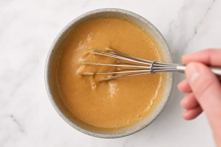 Batir la salsa de maní en un tazón pequeño hasta que quede suave.