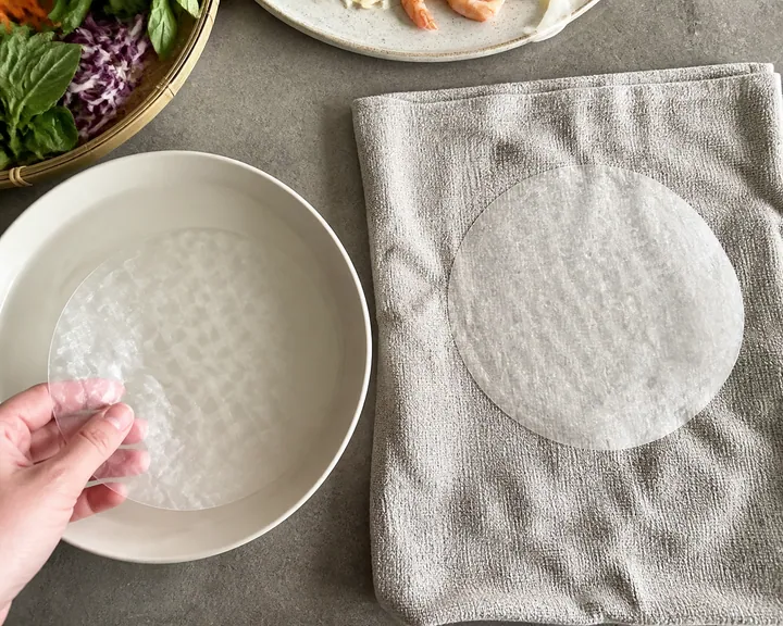 Una hoja de papel de arroz que se ablanda en agua tibia y se coloca sobre una toalla húmeda.