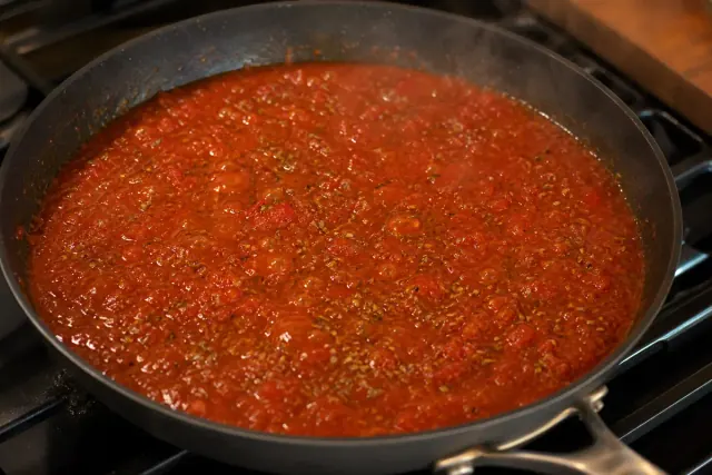 Salsa de tomate sazonada hirviendo suavemente en una sartén