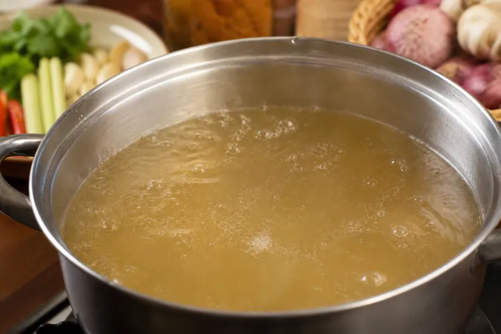 Chicken stock gently boiling in a medium pot