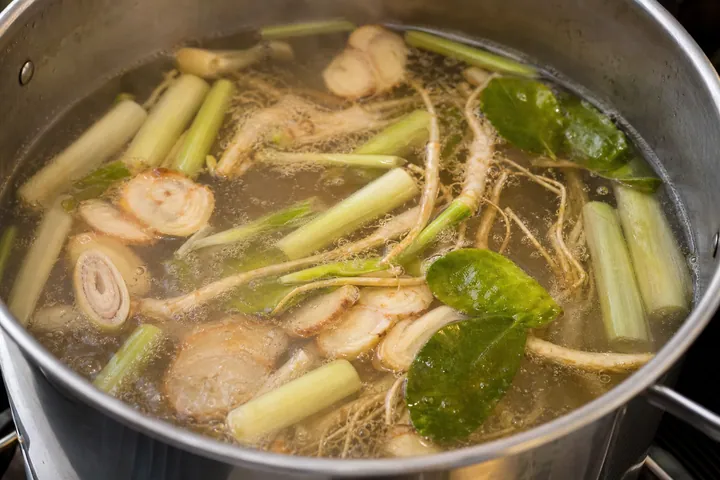 Lemongrass, galangal, coriander roots, and lime leaves infusing in broth